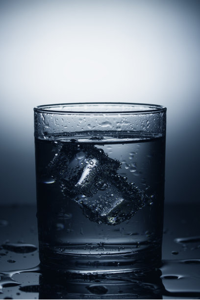一杯加冰的矿泉水。戏剧性的光线图片下载