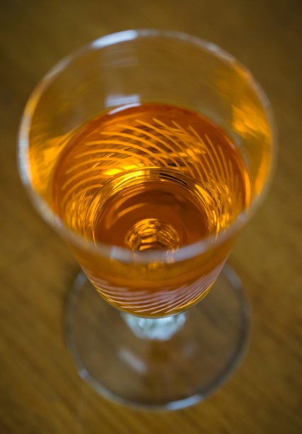木桌上摆着一只饰有橙色烈酒的小酒杯图片下载