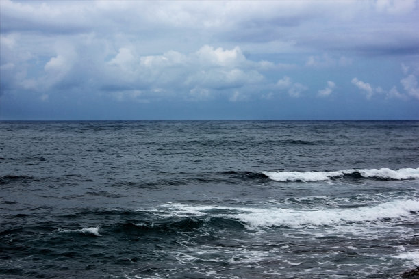 蓝色的大海。蓝色的天空。天空中有云。景观。大海并不平静。波。阳光正穿过天空图片下载