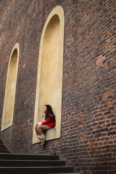 亚洲女游客坐在城市的墙上图片下载