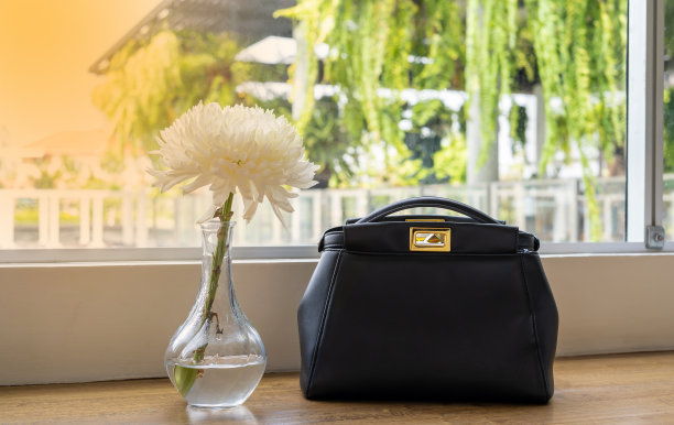 白色的花和黑色的包，放置在咖啡店的桌子与橙色的灯光图片下载