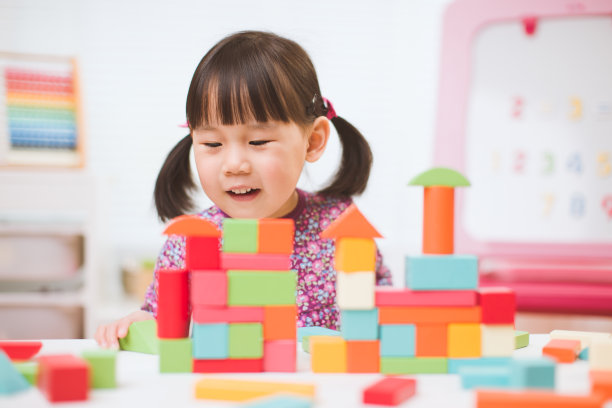 蹒跚学步的女孩在家里玩创意玩具积木的白色背景图片下载