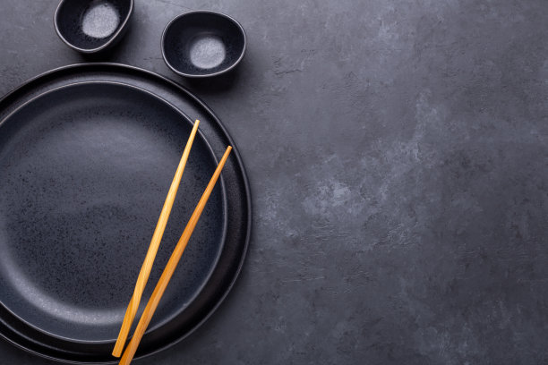 一套黑色的盘子和筷子在石头背景。适合亚洲、日本和中国食物图片下载