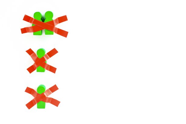 玩具木制的人用胶带粘在白色的墙上。在新冠肺炎大流行期间保持身体隔离、在家、社交距离、隔离、强制隔离、禁闭的概念。图片下载