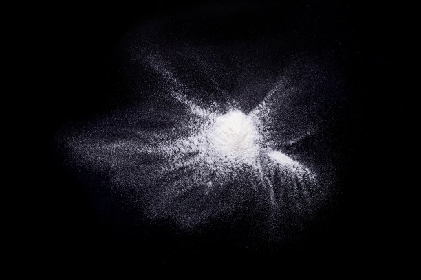 白色粉末在黑色背景上爆炸。停止白色粉末在黑色背景上的移动。发射白色粉末飞溅图片下载