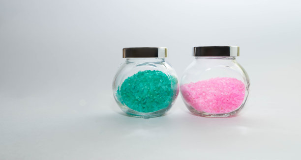 两个装有淡粉色和绿松石色浴盐的透明罐子。金属覆盖。白色背景上的水平照片。个人护理和水疗配件的概念。图片下载
