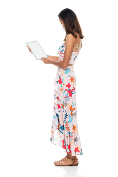 年轻女性穿着长裙站在白色背景前使用触摸屏图片下载
