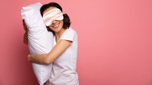 柔软的枕头。这是一名喜极而泣的女子的特写照片，她抱着枕头，眼睛上戴着口罩。图片下载