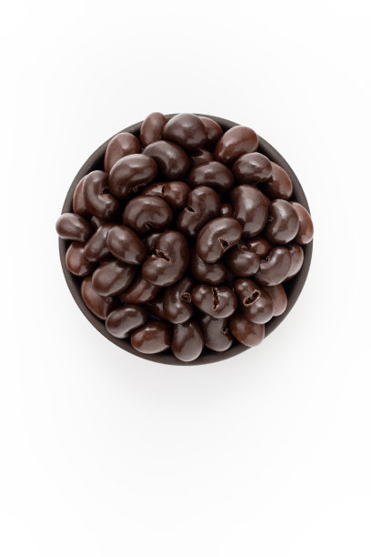 白色背景上的圆碗里的腰果巧克力，俯视图图片下载