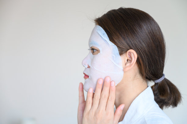 年轻妇女的肖像，用面膜增强她的皮肤，侧面。图片下载