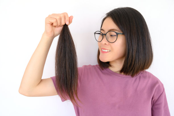 有吸引力的亚洲女人的肖像拿着一个马尾辫剪头发捐赠。图片下载