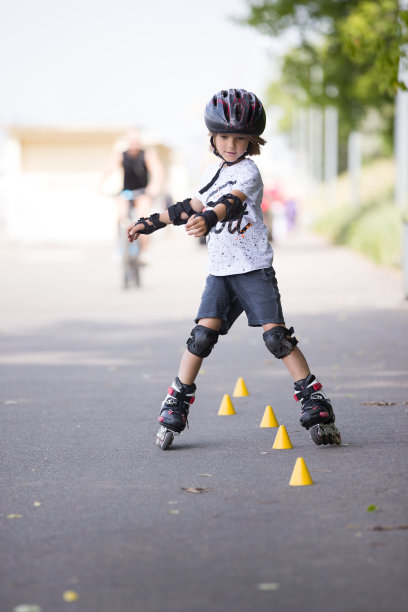 一个小男孩在公园里滑旱冰，在柏油路上扭来扭去图片下载