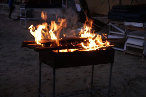 咆哮的，跳舞的火焰从海滩烧烤燃烧木材的夜晚天空，户外海滩餐厅图片下载