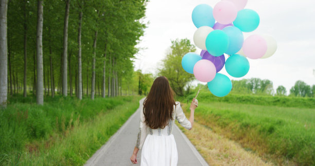 年轻的女人穿着维多利亚时代的裙子和彩色的气球在树林里图片下载