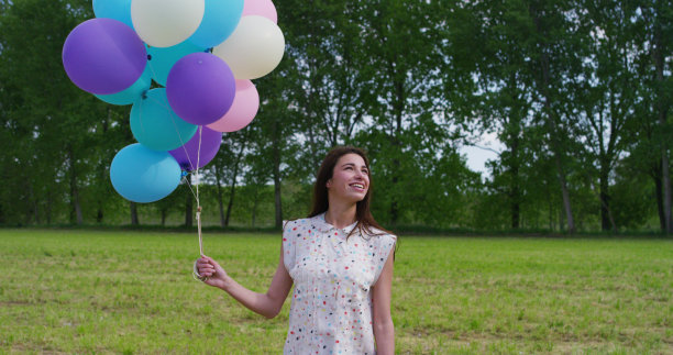年轻的女人穿着维多利亚时代的裙子和彩色的气球在树林里图片下载