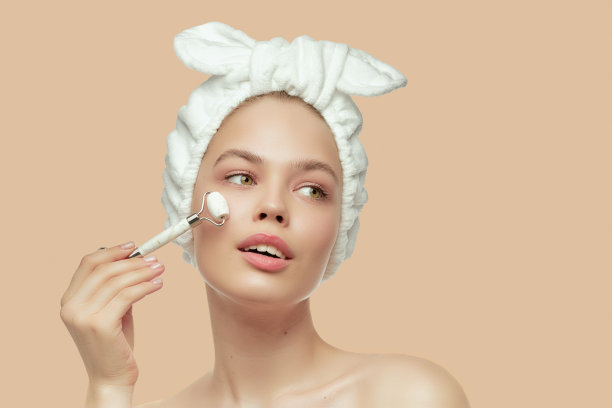 头上缠着绷带的女孩用美丽的刮沙玉石英石滚轮。满意的微笑。完美容光焕发，按摩。图片下载