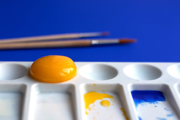 白色调色板与水彩颜料和画笔。蓝色背景。用蛋黄代替黄色。创意设计和艺术。俯视图和复制空间图片下载