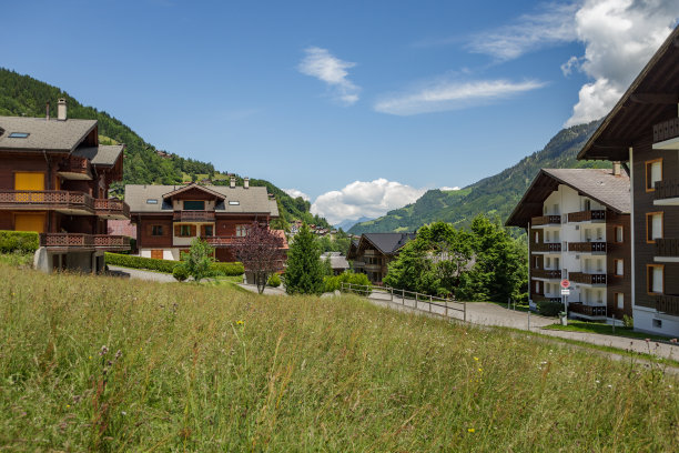瑞士尚佩里度假村的瑞士阿尔卑斯山雪峰美景，蓝天白云，岩石山峰，木屋沿路图片下载