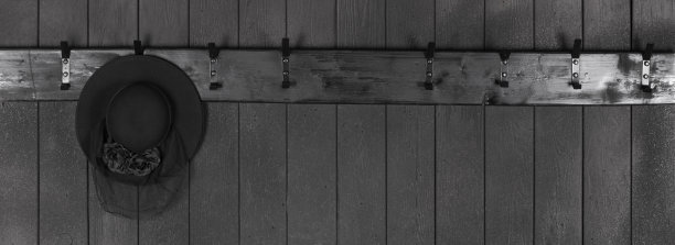 帽子挂在黑色木墙上的黑色木衣架上图片下载