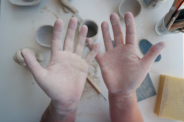 一位女性陶艺艺术家的手在作坊的桌子上。图片下载