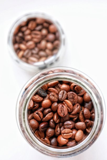 烤咖啡豆在一个透明的玻璃罐在一个白色的背景特写图片下载