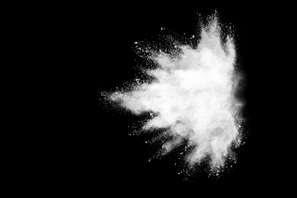 白色粉末在黑暗背景上爆炸的冻结运动。素材图片
