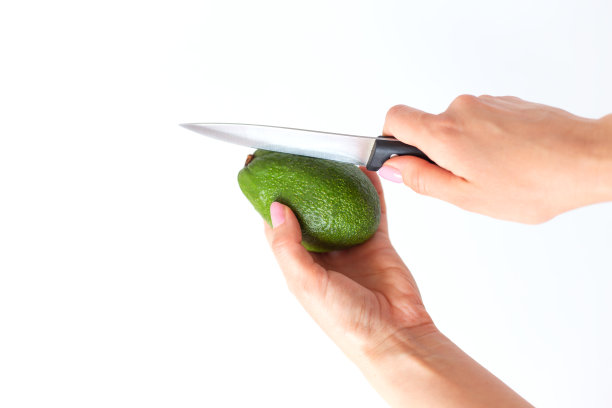手用刀在白色背景上切牛油果图片下载