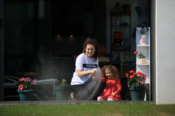 可爱的女孩和她的妈妈在浇花和草图片下载