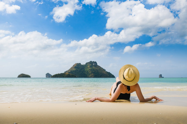 戴帽子的女人躺在美丽的海滩上图片下载