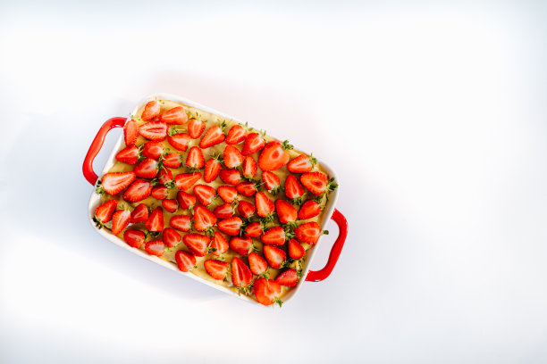 白色背景上的红色陶瓷烤盘上的草莓派图片下载