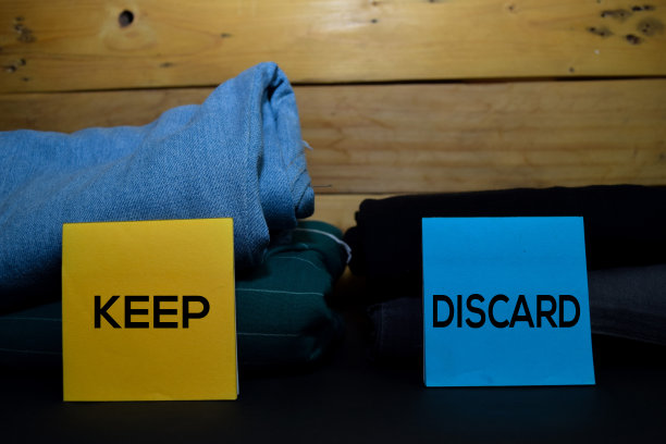 保存和丢弃写在时尚衣服之间的便利贴，折叠和堆放在木制的背景上。图片下载