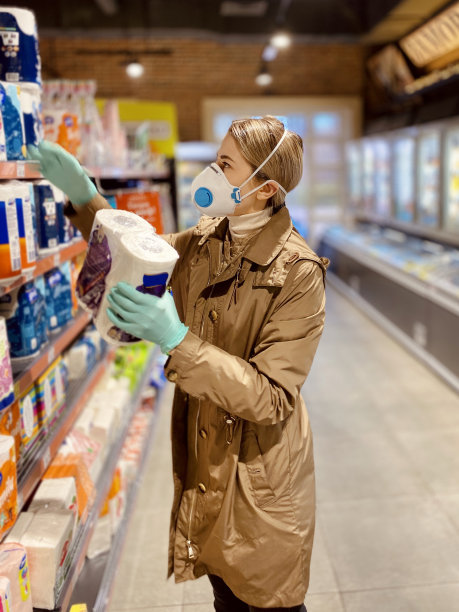 在超市里戴着防护口罩和手套的女孩。手里拿着卫生纸。美丽的年轻女子。新型冠状病毒肺炎Covid-20。图片下载