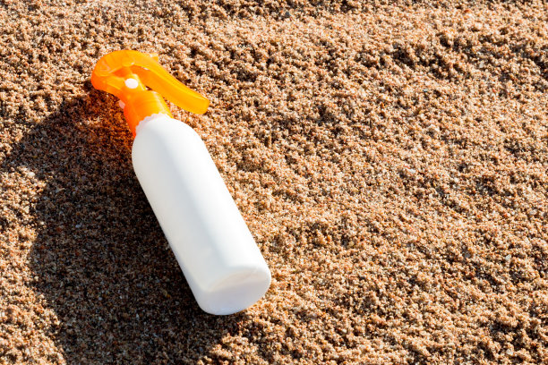 沙滩上带有空白区域的防晒霜白瓶，夏季防晒霜概念图片下载