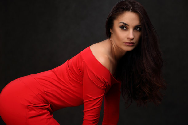 一个穿着红色裙子的漂亮女人的肖像，背景是黑色的图片下载