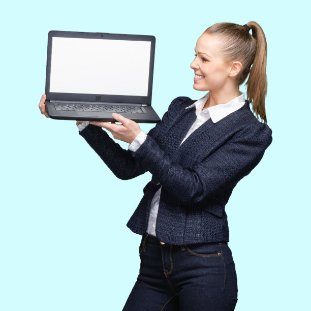 z一代年轻女性穿着运动夹克站在蓝色背景前，使用笔记本电脑图片下载