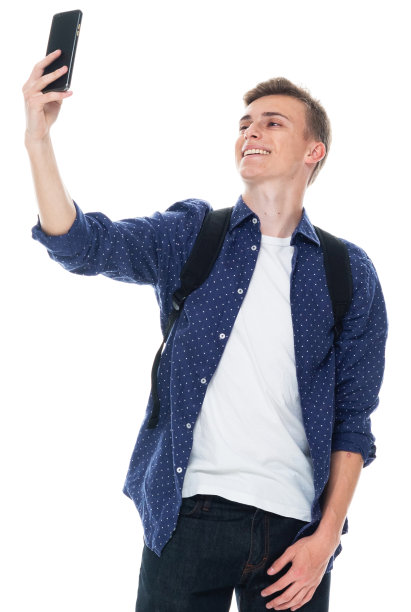 白人年轻男性穿着t恤站在白色背景前用手机拍照图片下载