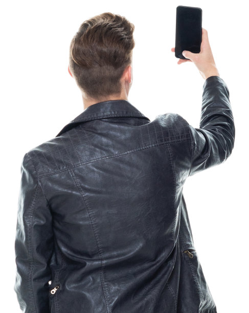 白人男孩穿着t恤站在白色背景前用手机拍照图片下载