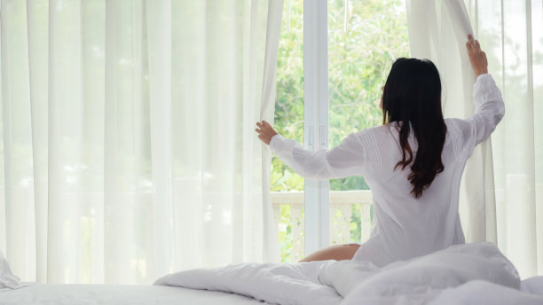 亚洲女性醒来后会在家里的卧室里做伸展运动和举起手臂。年轻人清晨时分，阳光明媚。生活方式的概念图片下载