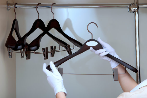 女佣正拿着一个衣架。衣架上有标识的空间。认不出来照片。酒店经营的概念。副本的空间。图片下载