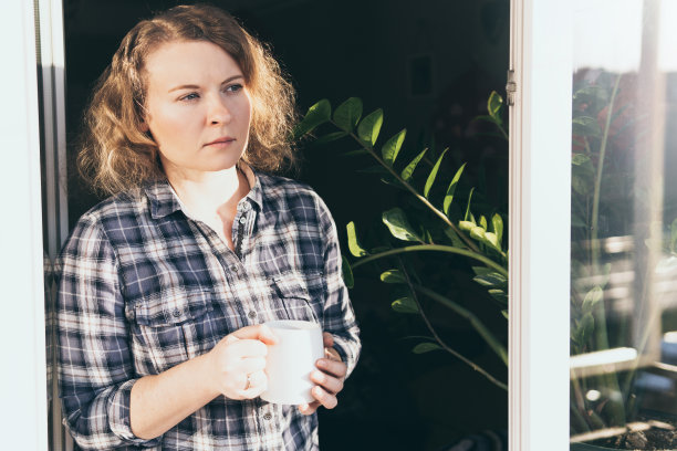 年轻的金发女人看着窗外，脸上带着关切的表情图片下载