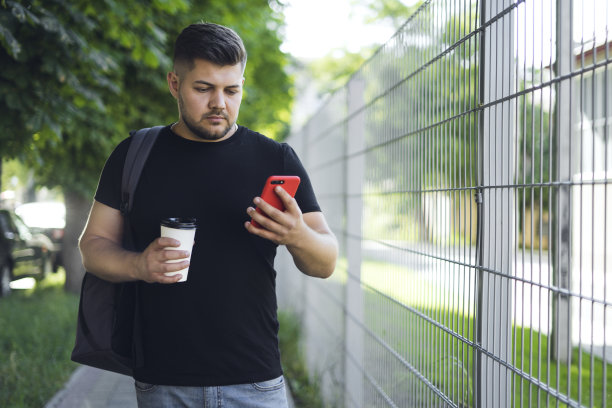 一个穿着黑色t恤留着胡子的男人正在用手机图片下载
