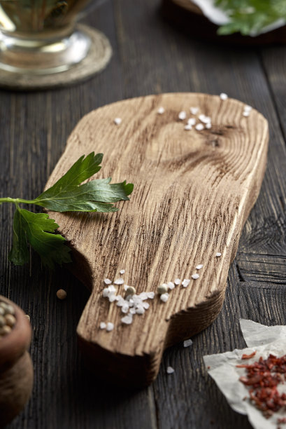 粗糙的盐和欧芹放在旧木桌上，特写的背景是有油的玻璃器皿。有拷贝空间的照片。图片下载