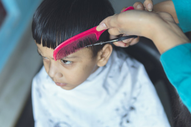 母亲在家给孩子剪头发。生活在封锁。图片下载