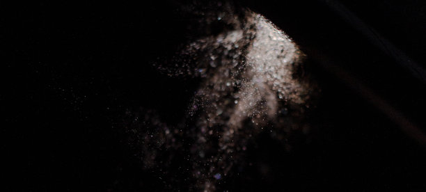 一个化妆刷的图像，扔在白色散粉，在黑色的背景上拍摄。图片下载