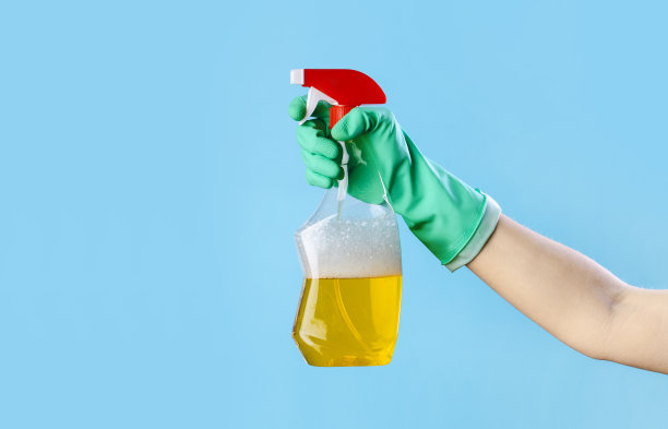 女手戴手套拿着蓝色背景上的窗户喷雾剂图片下载