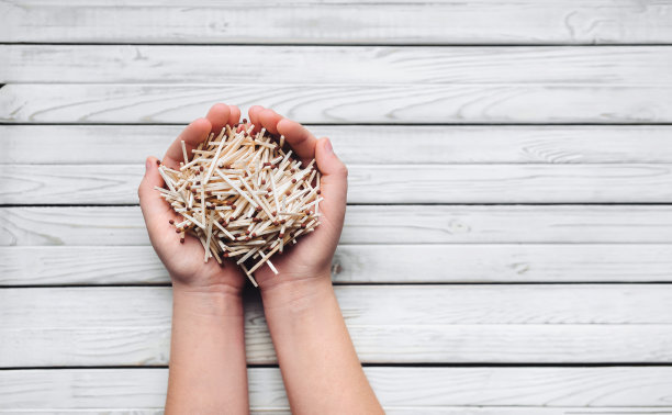 一个木头背景上的女孩手里拿着一大把火柴。概念和摄影。废物垃圾。简单的点火。图片下载