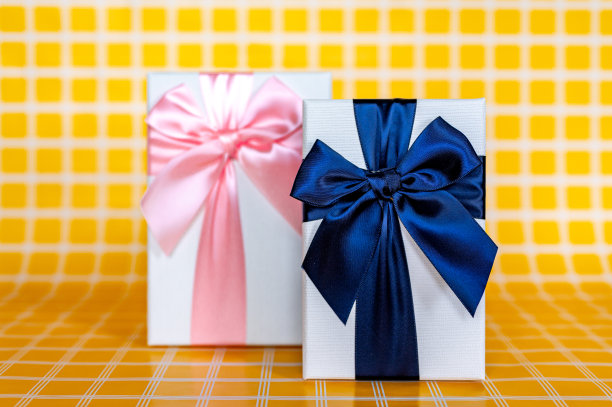 两个白色礼品盒，一个是粉色的，一个是蓝色的，上面有一张黄色格子的背景照片图片下载