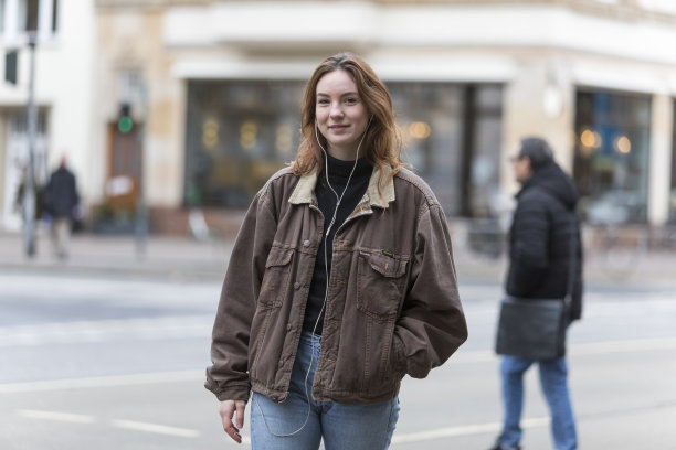 年轻女子一边听耳机一边对着镜头微笑图片下载