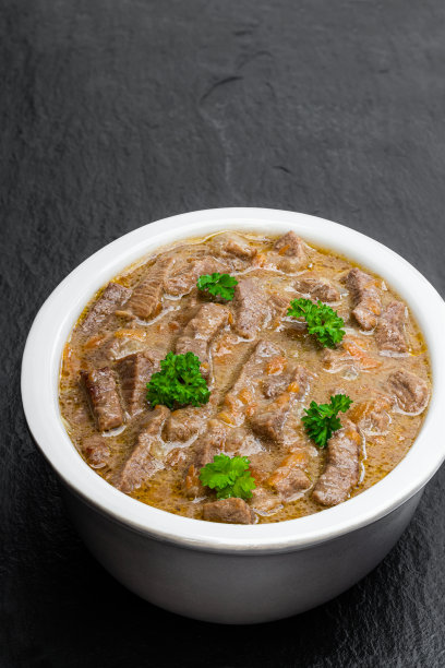 黑石背景上的陶碗蔬菜炖牛肉图片下载