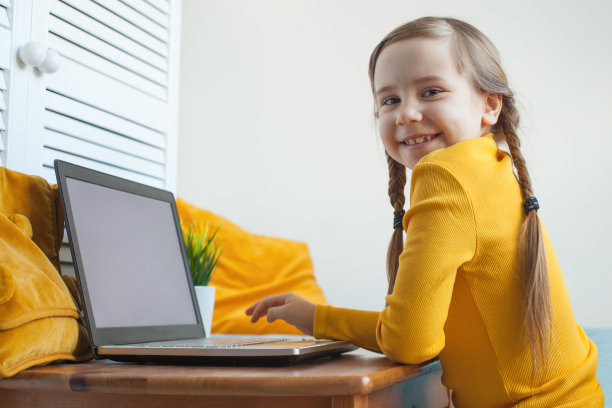一个小女孩在家里用一台空显示器的笔记本电脑图片下载
